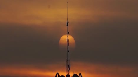static shot of the rising sun during sunrise behind an antenna in mexico city