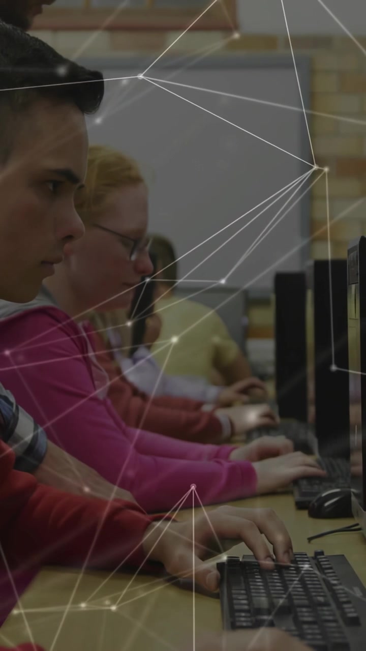 Vertical video: Male teen typing at keyboard, peers typing in school lab, node overlay drifting