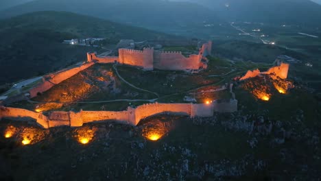 drone footage over an illuminated medieval castle at dusk