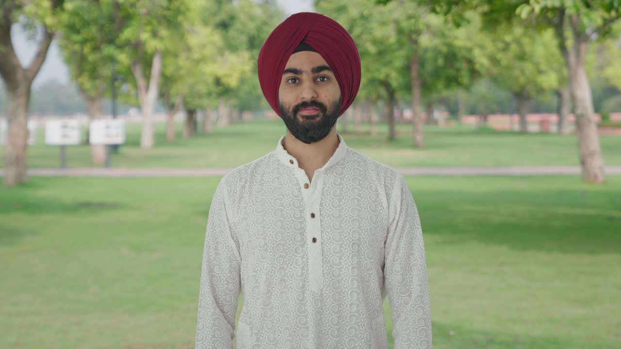 Uomo indiano Sikh felice che sorride nel parco.