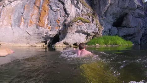 man swimming in a rocky river