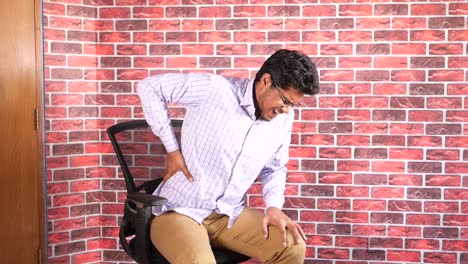 man experiencing back pain while sitting in office chair