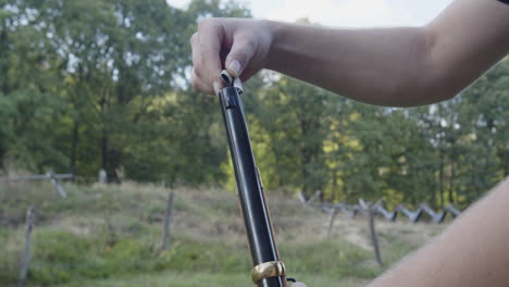 person sprinkles gunpowder down the barrel of a musket