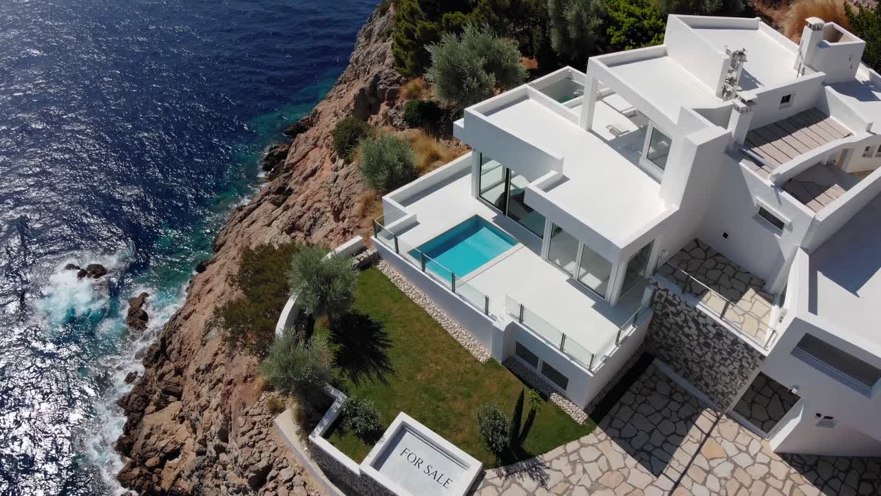 Luxurious white villa perched on Mediterranean cliff, featuring infinity pool, expansive garden, panoramic sea views, symbolizing high end real estate and hospitality potential