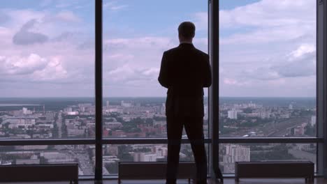 businessman contemplating city view from skyscraper