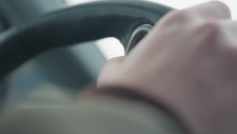 close up of person pressing button on steering wheel showing finger contact with control switch visual detail in modern car cabin interior under natural daylight highlighting ergonomic design