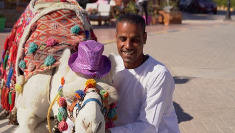 arab man kissing a camel in a touristic area.