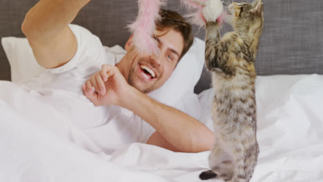 smiling young man lying on bed playing with his tabby cat 4k 4k