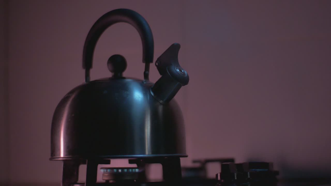 Boiling Water Hot Steam Rushes From A Metal Kettle Heated On A Gas Stove In The Kitchen. Warm Purple Tone Background