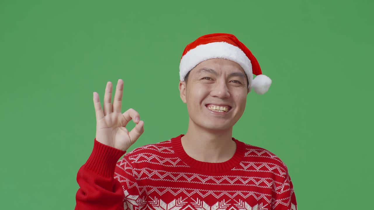 산타 모자와 빨간 스웨터를 입은 남자가 ok 손짓을 하고 있습니다.