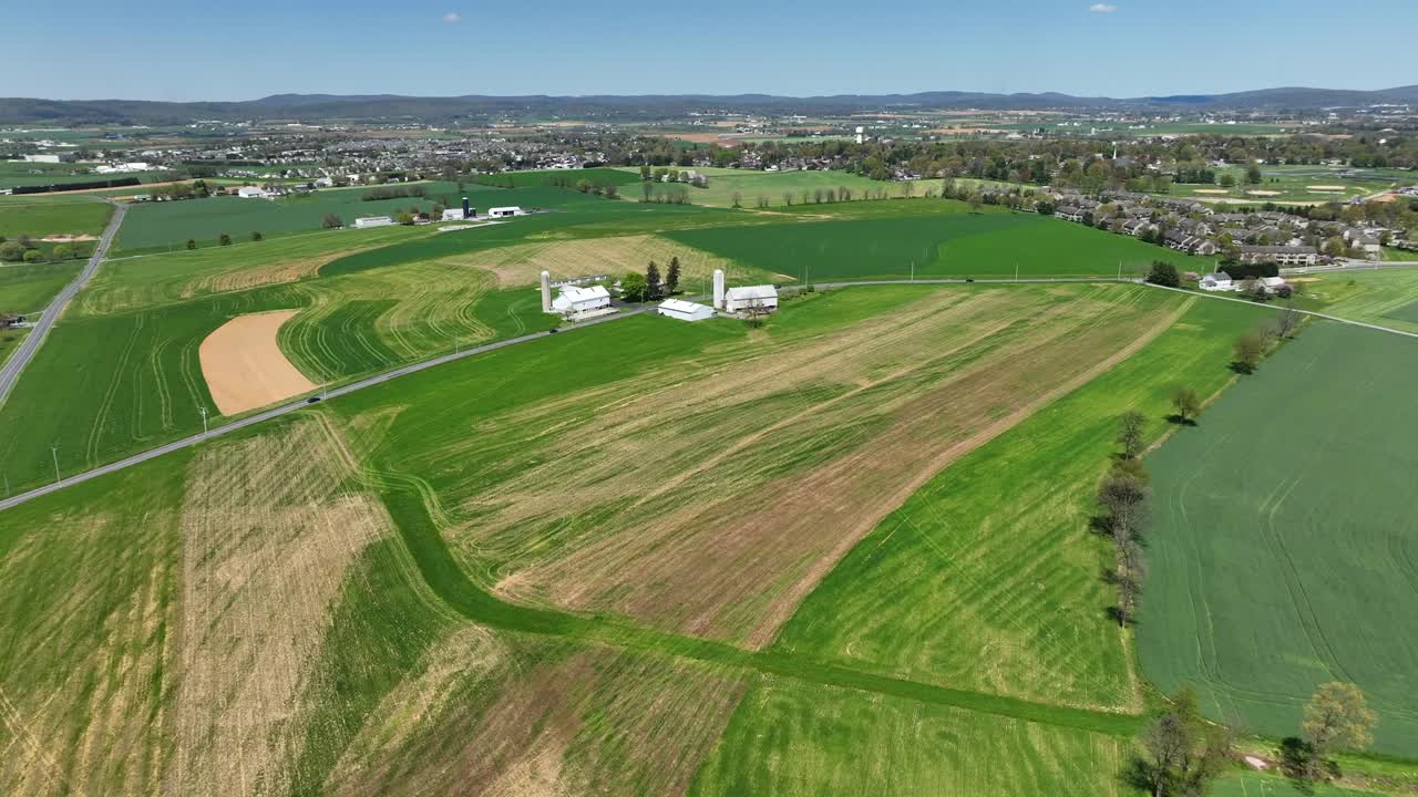 Driving cars on rural road surrounded by farm fields with dried pattern on hot summer day