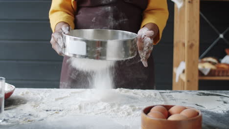 una panadera afroamericana irreconocible tamizando la harina