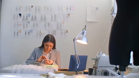 a young woman designer making a dress in the studio dress. tailoring studio sewing beads and jewelry. seamstress decorates a dress in the studio.