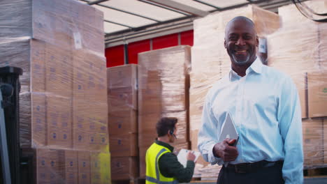 Portrait-Of-Mature-Male-Freight-Haulage-Manager-Standing-By-Lorry-Being-Loaded-With-Boxes