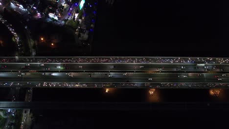 antena aérea vista de pájaro perspectiva del tráfico en saigón vietnam con autos ocupados y tráfico de scooters conduciendo en un puente por la noche