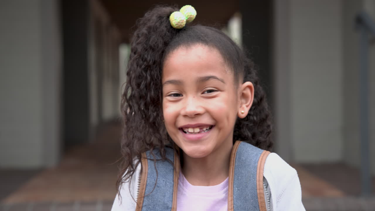 Smiling African American girl with backpack outside school, looking cheerful