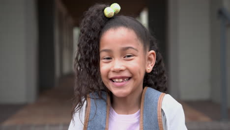 smiling african american girl with backpack outside school, looking cheerful