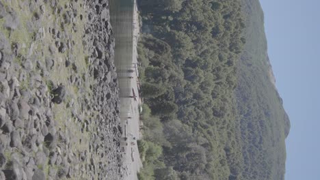 Un-Lago-Tranquilo-Con-Gente-Relajándose-En-La-Orilla-Con-Montañas-Y-Bosques-En-Patagonia,-Argentina