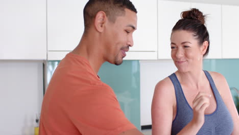 smiling couple enjoying time together in kitchen, woman in workout clothes