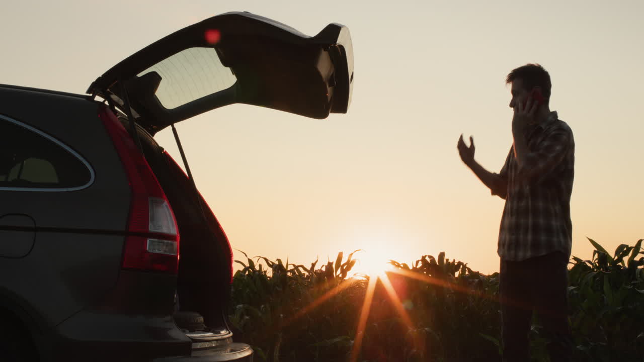 разгневанный мужчина разговаривает по телефону. он стоит у своей машины на обочине дороги.