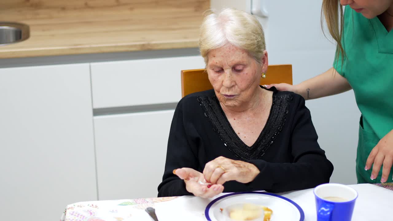 Elderly woman assisted by caregiver drinking water