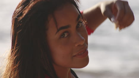 closeup head shot of attractive latin woman relaxing on beach turns around to look back at camera