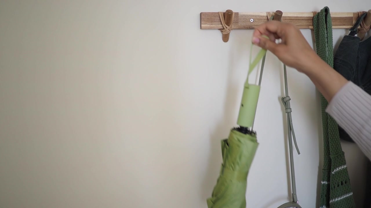 Ombrello verde appeso a un gancio da parete in legno