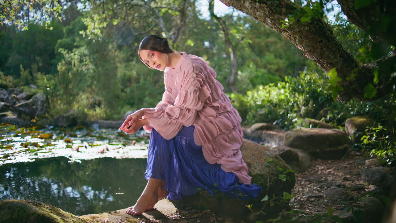 패션 소녀 앉아 호수 마법의 숲에서 빛 날. 환상 모델 포징 연못
