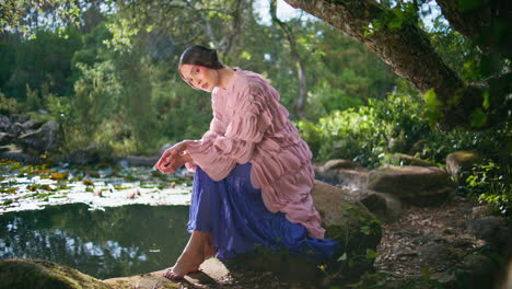 chica de moda sentada en el lago bosque mágico en un día soleado modelo de fantasía posando estanque