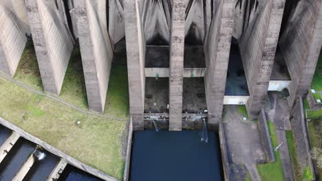 aerial top down view over concrete dam at wimbleball lake with tilt up reveal of buttress structure