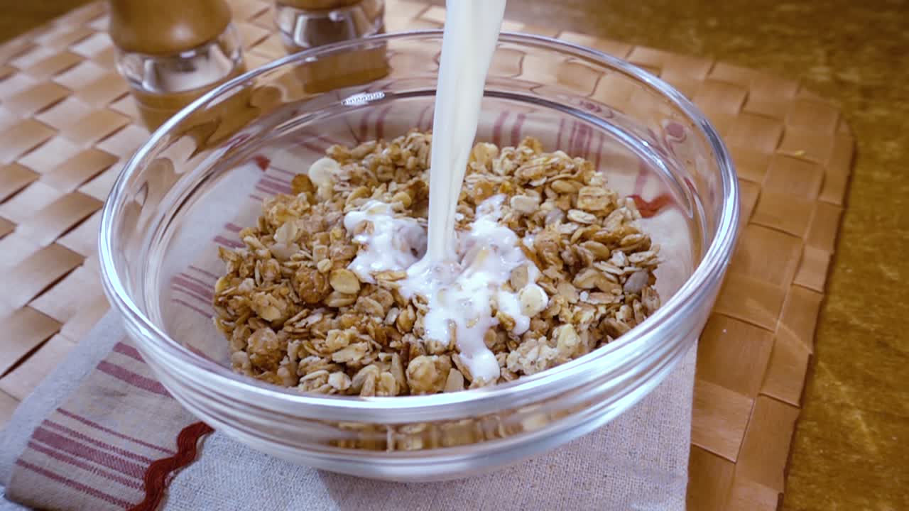 muesli de cereales de grano entero en un tazón para un delicioso desayuno matutino con leche. cámara lenta con toma de seguimiento de rotación.