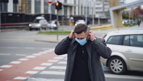 guy with medical mask outdoors. young businessman in smart casual walking during pandemic