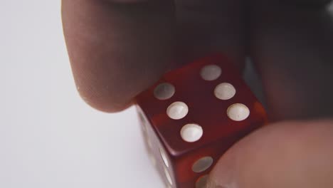 La-Persona-Sostiene-Dados-Rojos-Con-El-Símbolo-Seis-En-Una-Macro-De-Superficie-Blanca.