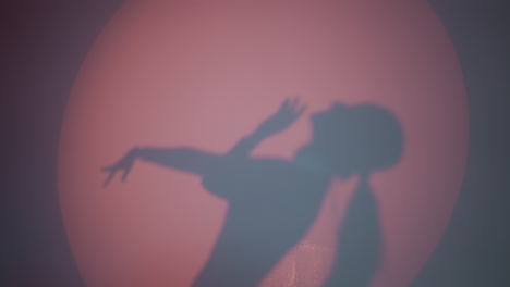 a dancing lady's shadow reflecting on the wall, moving hands slowly and gently against a red background. the silhouette captures a graceful and artistic motion