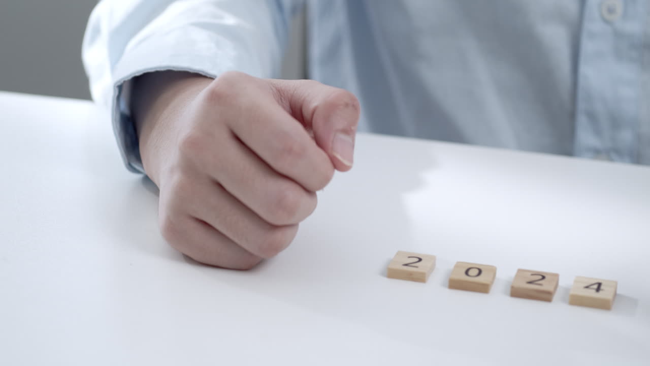 Person placing wooden blocks with numbers 2024, symbolizing New Year's resolutions