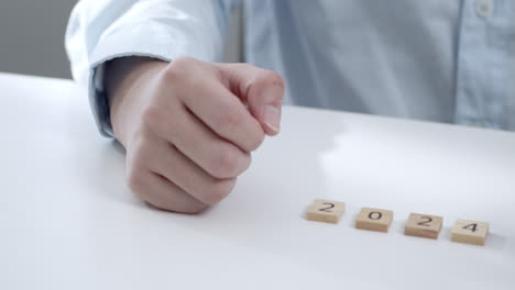 person placing wooden blocks with numbers 2024, symbolizing new year's resolutions