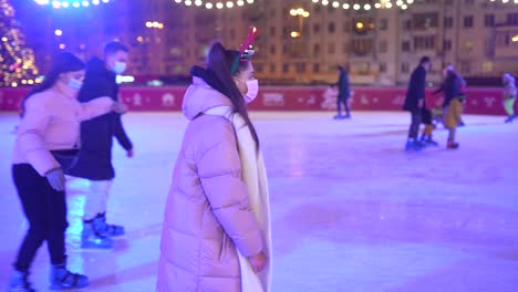 mujer patinando sobre hielo en una pista de patinaje de navidad por la noche