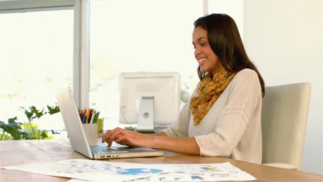 una chica bonita usando una computadora portátil en un escritorio