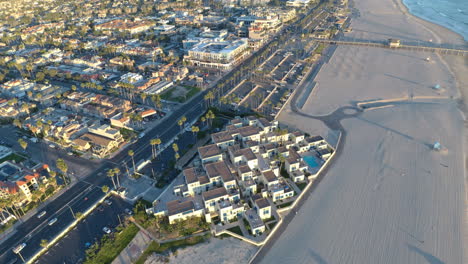 a 4k aerial drone shot of beachfront condos pulls back to reveal the ocean and a pier.