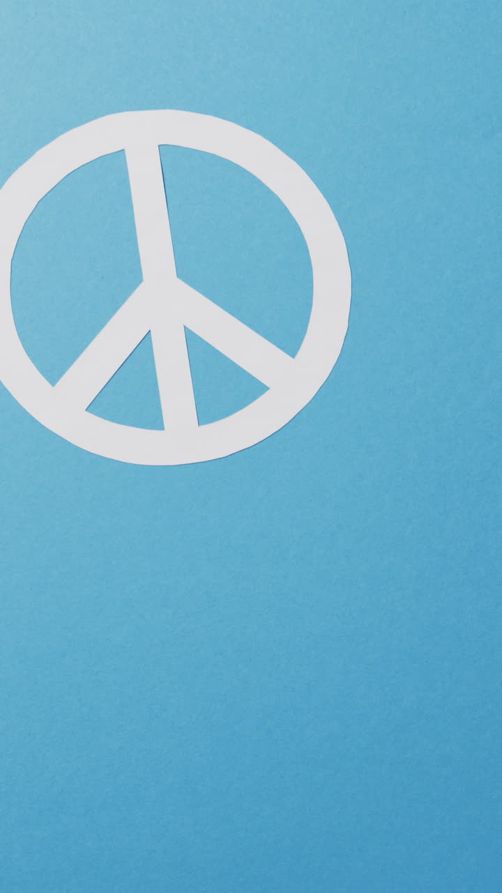 Vertical video of white peace sign and copy space on blue background