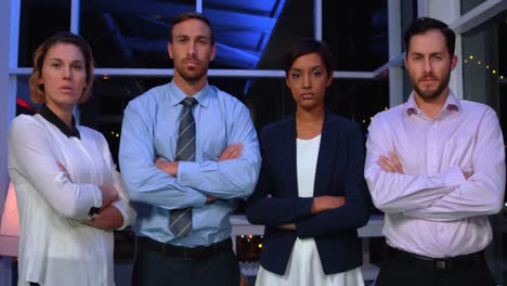 Businesspeople-standing-with-arms-crossed-in-office-at-night