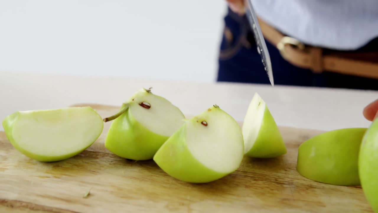 mujer cortando manzana verde en la tabla de cortar