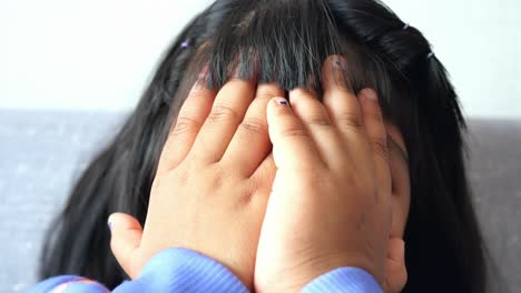 young girl covering her face with her hands