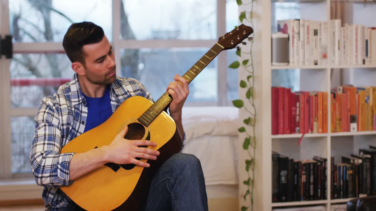 집 의 거실 에서 기타 를 연주 하는 남자