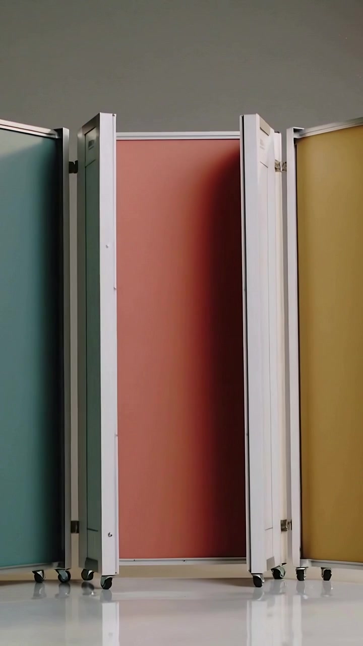 Video verticale: Parete divisoria che si dispiega in studio, ruotando sui cardini e spostandosi su ruote, rivelando i colori verde acqua, corallo e senape