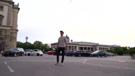 An epic rotating shot of a young filmmaker holding a heavy camera in front of an important building