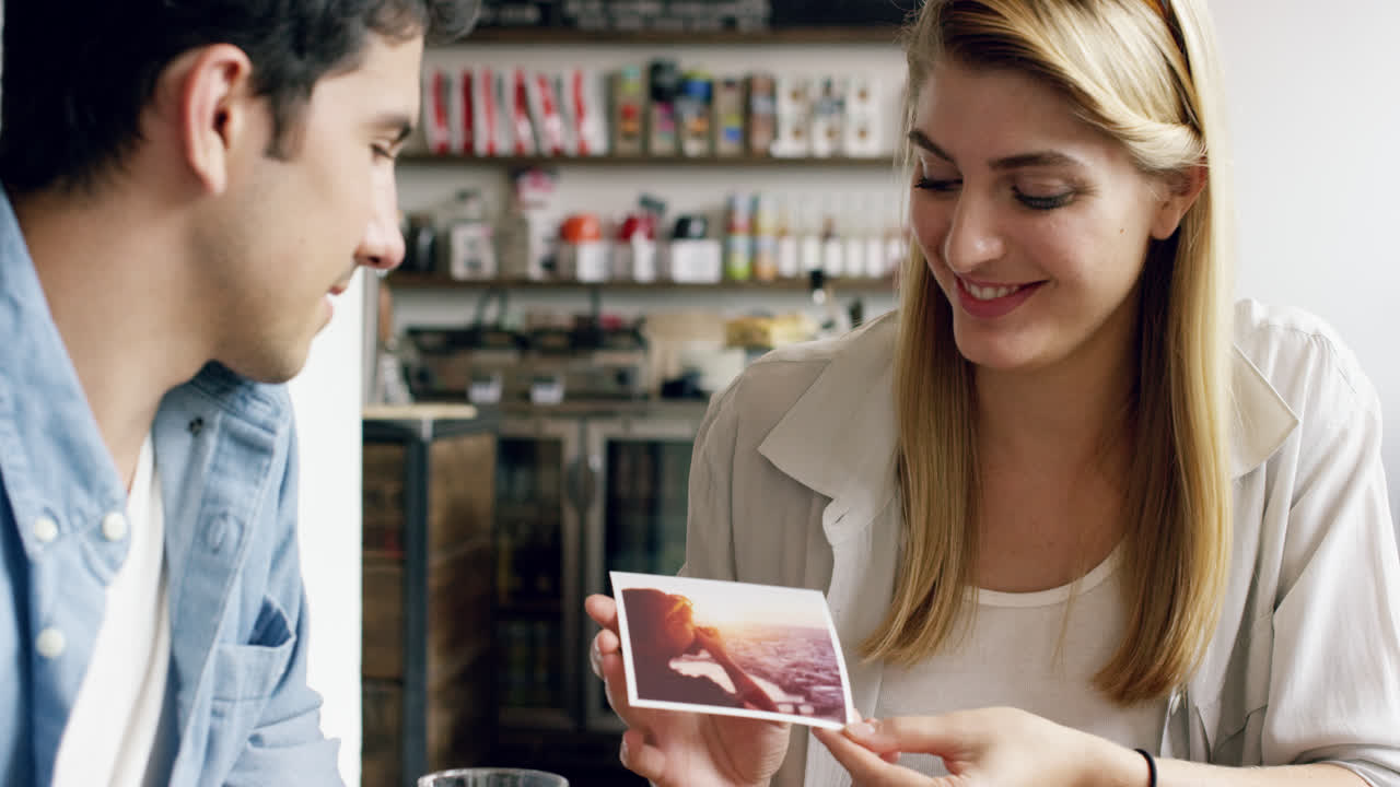 grupo de jóvenes de raza mixta se reúnen en un café mostrando fotografías