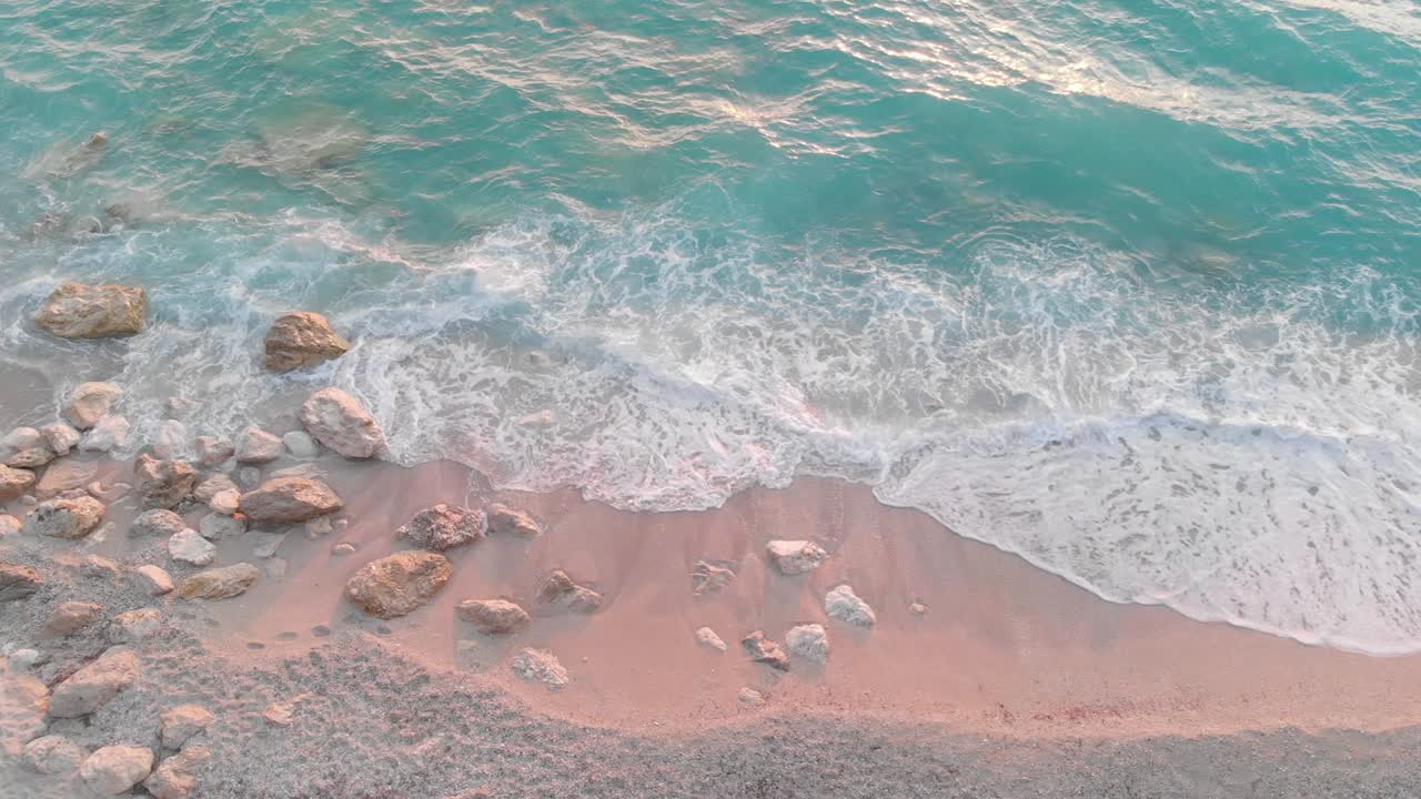 волны бьются о скалы на песчаном пляже при заходе солнца, сняты с дрона