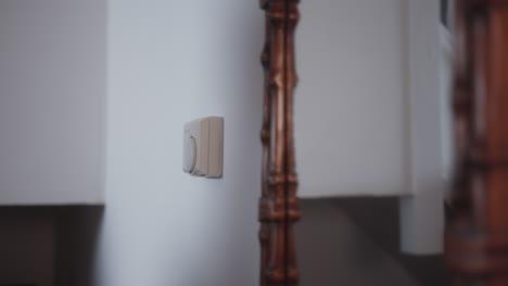 man adjusting the dial on thermostat, lowering the temperature to save on energy bills during the cost of living crisis