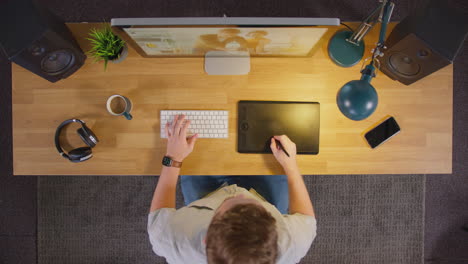 Vista-Aérea-De-Un-Diseñador-Gráfico-Masculino-Trabajando-En-La-Pantalla-De-Una-Computadora-En-Una-Oficina-Creativa-Por-La-Noche